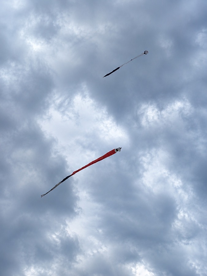 Long handmade kites flying high in a cloudy Karangasem sky